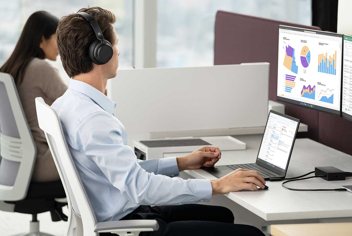 Man working at a workstation on a Surface Laptop 5 docked with two monitors