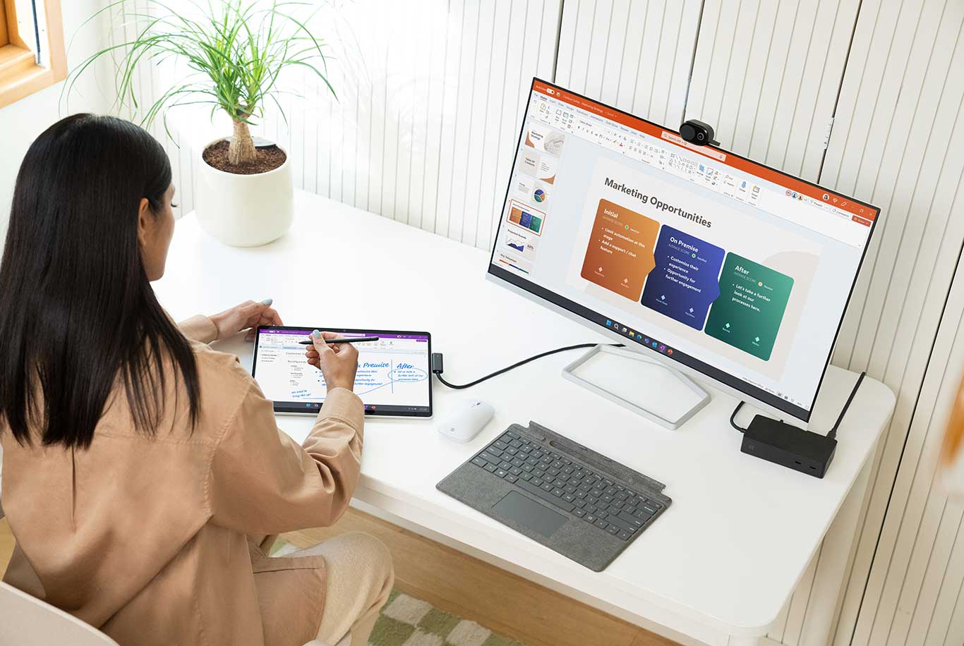 Woman at desk sketching on the Surface Pro 9 in tablet mode, which is also connected to an external monitor